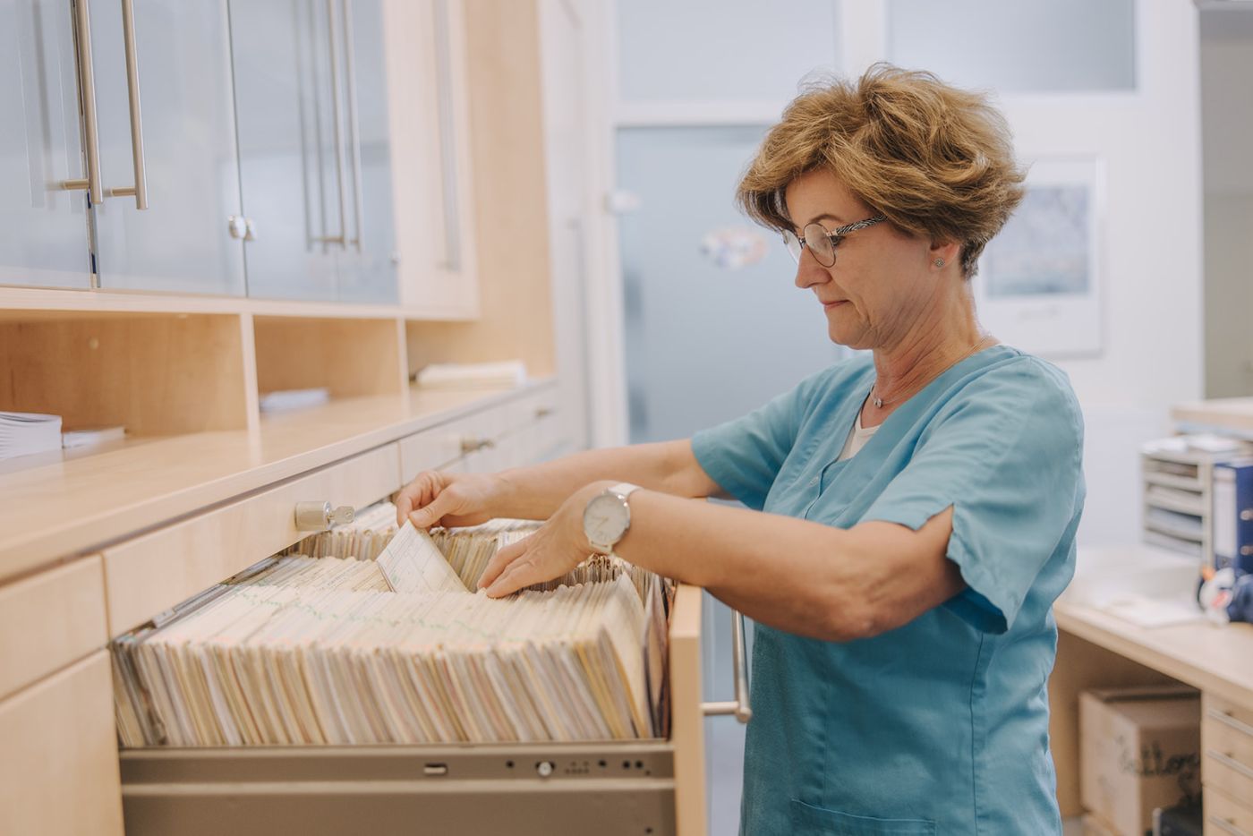 Mitarbeiterin der Hausarztpraxis Dr. Doßow in Magdeburg sortiert Patientenakten sorgfältig ein.