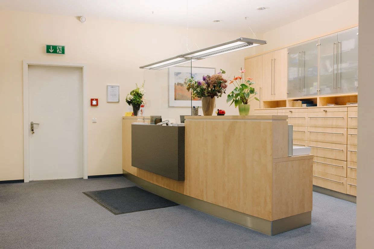 Heller Empfangsbereich der Hausarztpraxis Dr. Doßow in Magdeburg mit Blumen und freundlicher Atmosphäre.