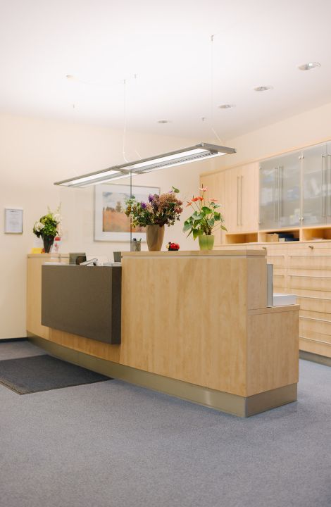 Freundlicher Empfangsbereich der Hausarztpraxis Dr. Hendrik Doßow in Magdeburg mit frischen Blumen.