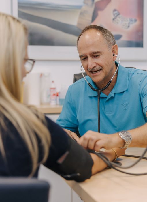 Hausarzt Dr. Doßow misst den Blutdruck einer Patientin in seiner Praxis in Magdeburg.