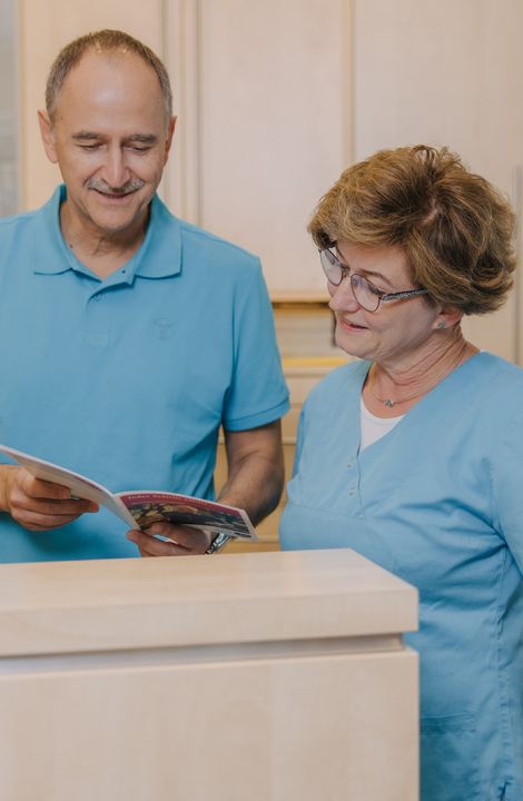 Hausarzt Dr. Doßow und Mitarbeiterin im Gespräch am Empfang der Praxis in Magdeburg.