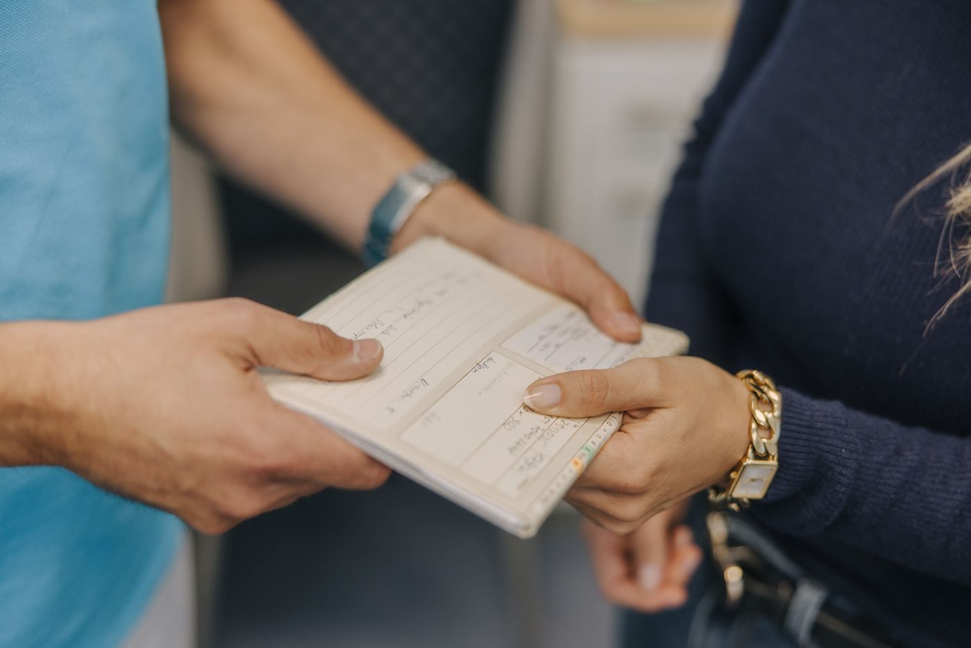Übergabe eines Impfpasses zwischen Arzt und Patientin in der Hausarztpraxis Dr. Doßow Magdeburg.