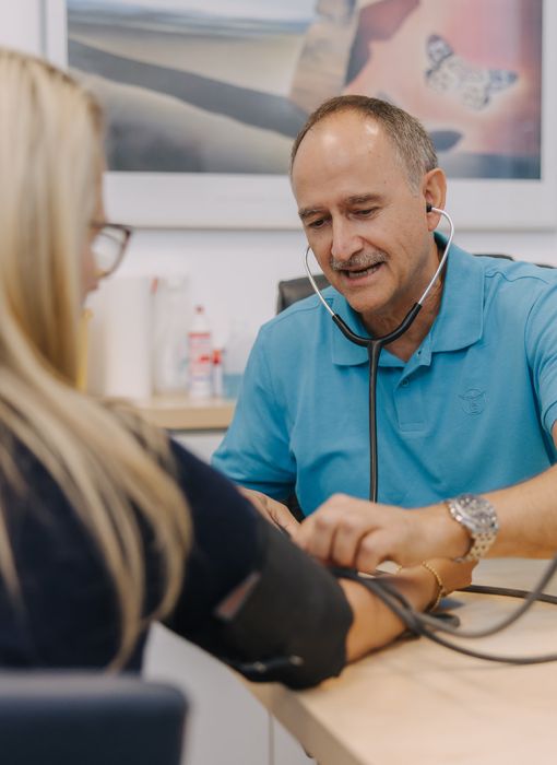 Hausarzt Dr. Doßow misst den Blutdruck einer Patientin in seiner Praxis in Magdeburg.