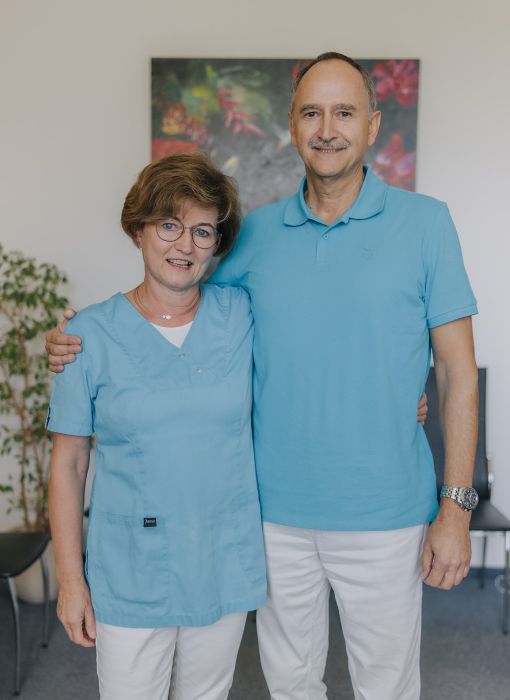 Hausarzt Dr. Doßow und Mitarbeiterin lächeln gemeinsam im Team der Praxis in Magdeburg