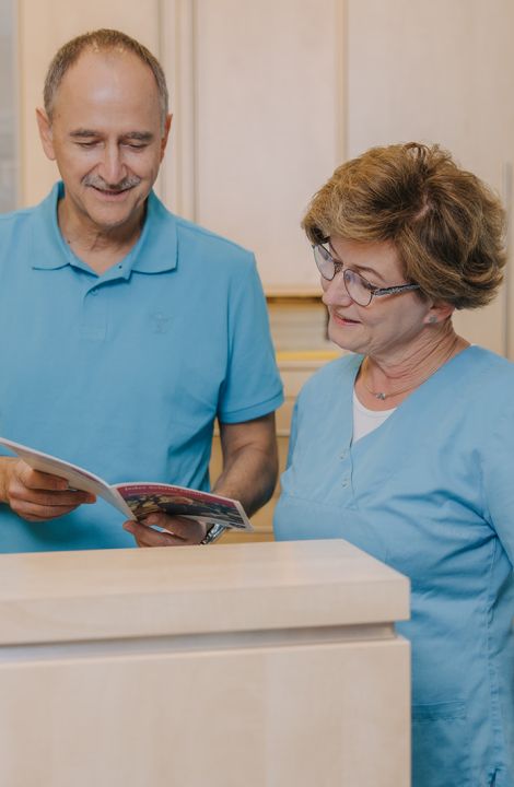 Hausarzt Dr. Doßow und Mitarbeiterin im Gespräch am Empfang der Praxis in Magdeburg.